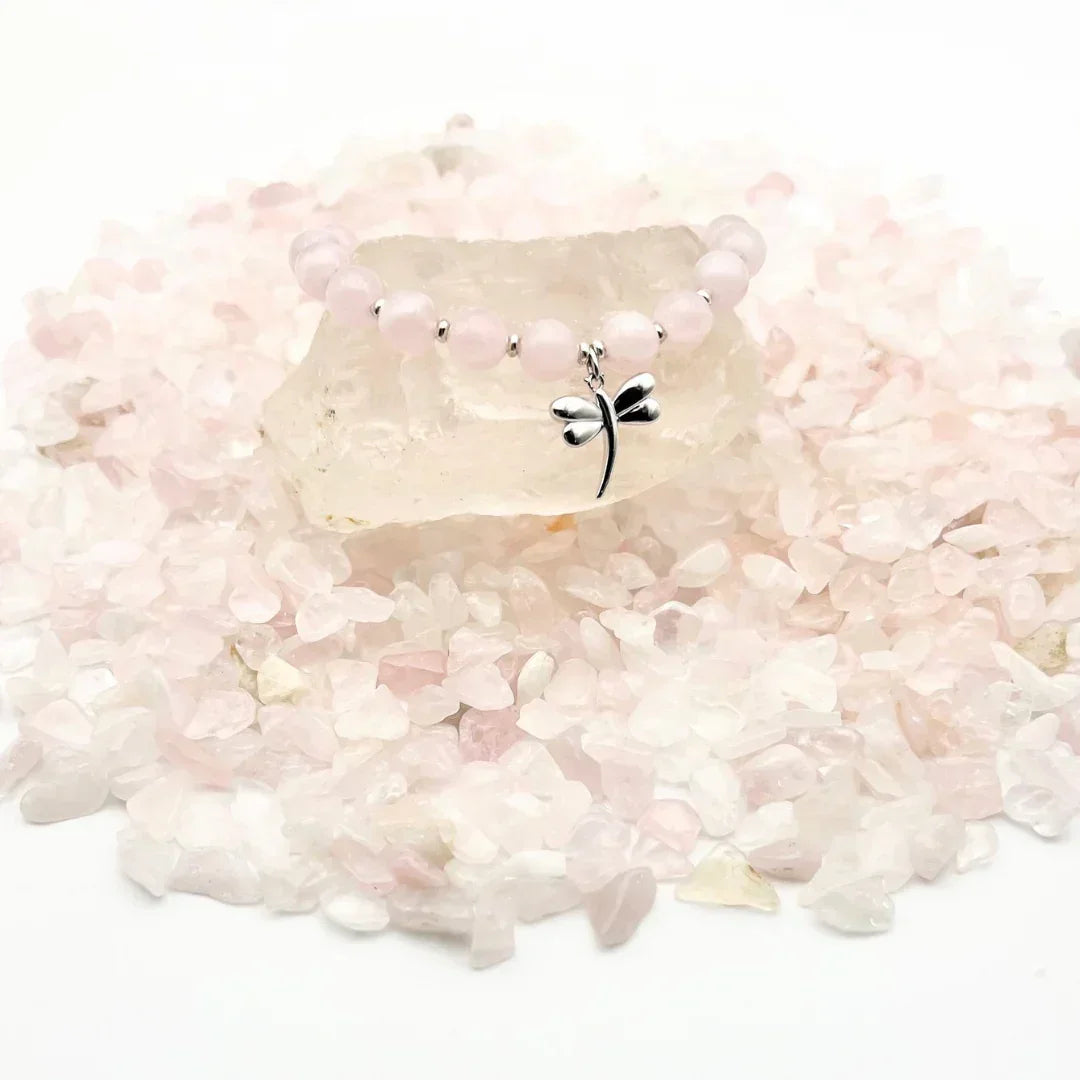 Rose Quartz crystal bracelet with a sterling silver dragonfly charm on a bed of crystals
